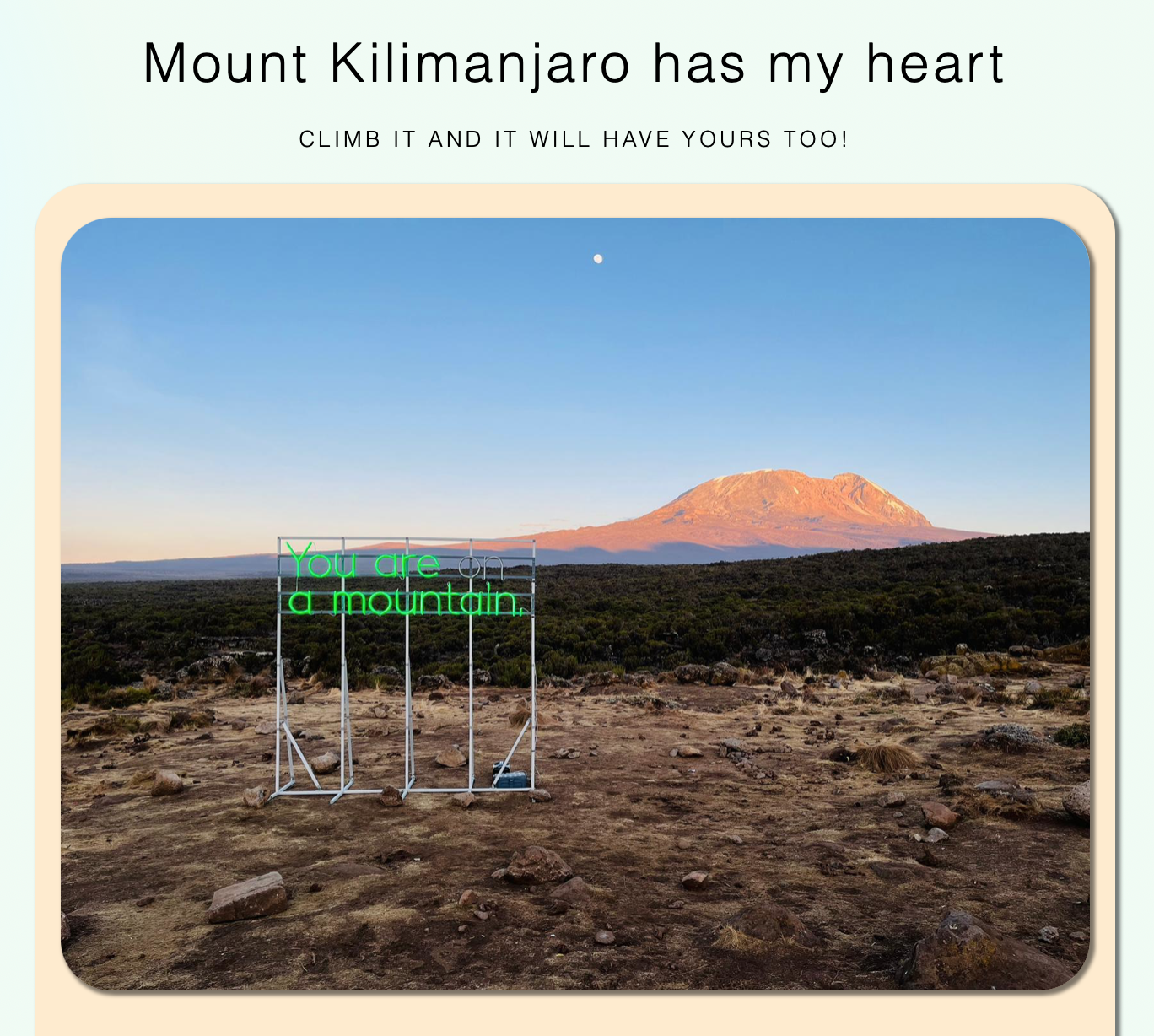 A sign that says'You are a mountain' with the top of Kilimanjaro in the background.